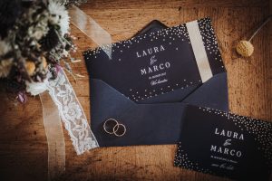Hochzeit von Laura und Marco in Münster: Hochzeitsringe, die auf der Hochzeitseinladung liegen