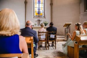 Hochzeit von Jennifer und Stefan in Münster: Brautpaar von hinten in der Kirche zu sehen
